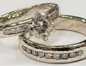 Estate Mokume-Gane Diamond Engagement Ring
18K/925 White Estate Engagement Ring
Finger Size 5.5 Gram Weight 7.5
1 Center Diamond 0.64ct Shape: Round; Clarity: I1; Colour: J With 17 Round Diamonds 0.26 ctw 0.9