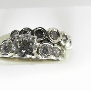 Estate Diamond Engagement Ring 
19 Karat White Estate Engagement Ring 
Finger Size 6 Gram Weight 6.7 
1 Center Diamond 0.61ct Shape: Round; Clarity: SI2; Colour: J; GIA 1116763845 With 13 Round Diamonds 0.68 ctw 1.29