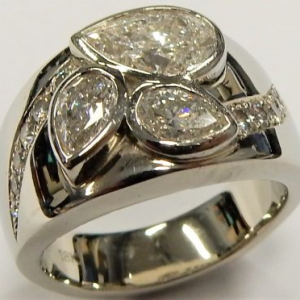 Estate Diamond Dinner Ring - Women's 
18 Karat White Estate Dinner Ring 
Finger Size 5.5 Gram Weight 14.6 
1 Center Diamond Shape: Pear; Clarity: I1; Colour: H With 2 Pear Diamonds 0.62 ctw and 12 Round Diamonds 0.22 ctw 0.84