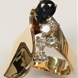 Sapphire Estate Ring 
14 Karat Yellow Blue Sapphire Ring 
 Gram Weight 7.57 
1 Center Sapphire 0.78ct Shape: Pear; Clarity: VS; Colour: Blue With 5 Round Diamonds 0.50 ctw