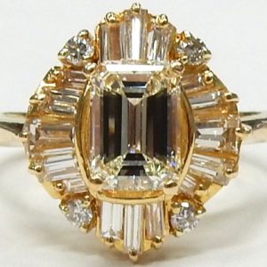 Estate Diamond Dinner Ring - Women's 
19 Karat Yellow Estate Dinner Ring Width 2.5mm 
Finger Size 8.5 Gram Weight 5.4 
1 Center Diamond; 1.40ct Shape: Emerald; Clarity: VVS; Colour: H With 4 Round Diamonds 0.12 ctw and 16 Baguette Diamonds 0.76 ctw 2.2