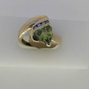 Peridot Ring 
10 Karat Yellow Peridot Ring With Finger Size 6.5 
Width 2.12mm Gram Weight 3.85 
1 Center Peridot Shape: Trillian With 4 Round Diamonds 0.06 ctw