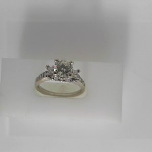 Estate Diamond Engagement Ring 
18 Karat White Estate Engagement Ring 
Finger Size 7.75 Gram Weight 4.96 
1 Center Diamond 1.03ct Shape: Round; Clarity: VVS2; Colour: K/L With 2 Princess Diamonds 0.20 ctw and 60 Round Diamonds 0.48 ctw 1.71