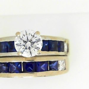 Estate Diamond Engagement Ring 
14 Karat White Estate Engagement Ring 
Finger Size 7.5 Gram Weight 12.1 
1 Center Diamond 1.00ct Shape: Round; Clarity: I1; Colour: D With 4 Princess Diamonds 0.60 ctw and 13 Princess Sapphires 2.08 ctw 3.68