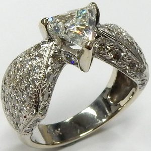 Estate Diamond Dinner Ring - Women's 
14 Karat White Estate Dinner Ring 
Finger Size 5.5 Gram Weight 6.9 
1 Center Diamond; 0.80ct Shape: Trillian; Clarity: I1; Colour: I With 96 Round Diamonds 1.05 ctw 1.85